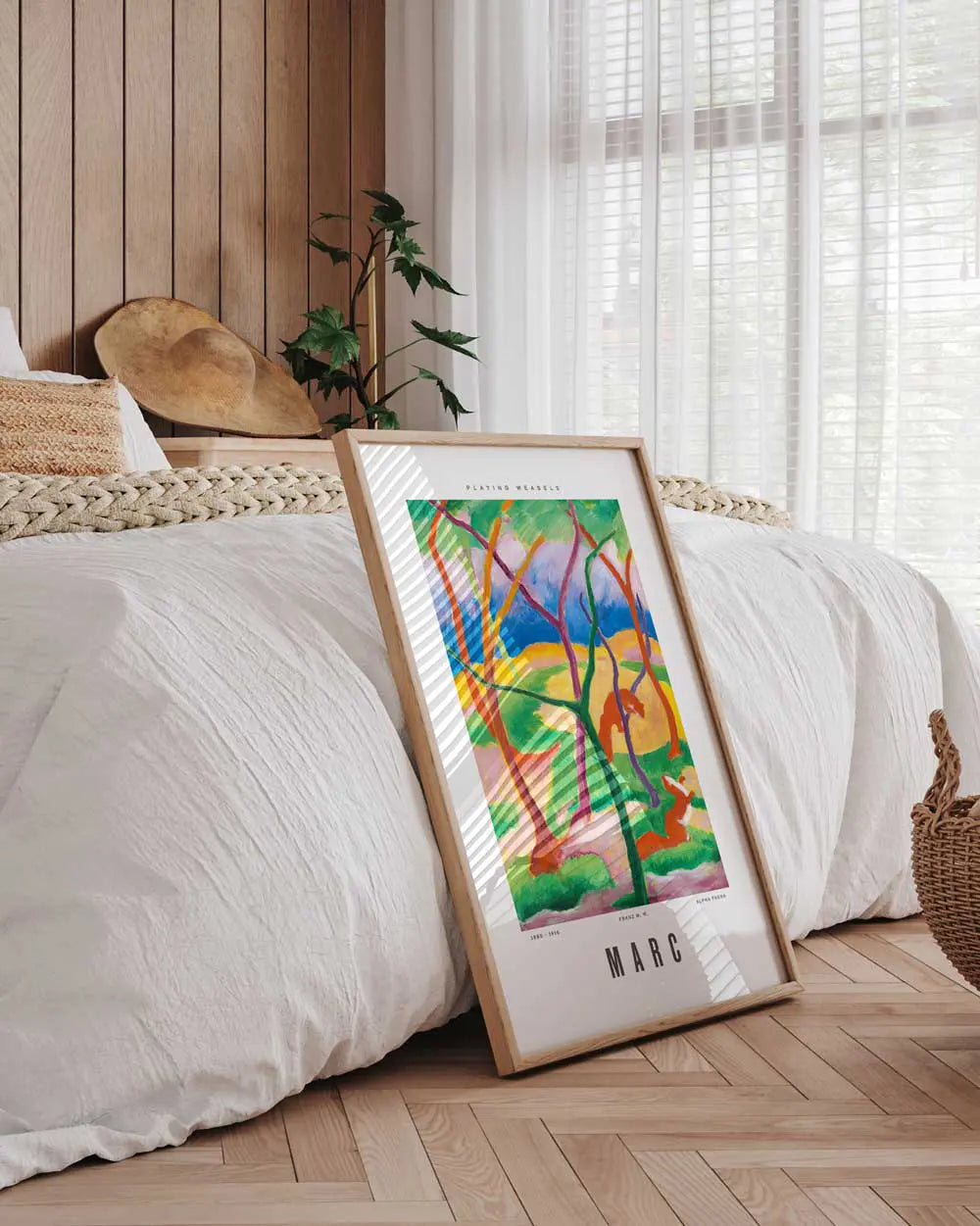 Framed colorful artwork on a wooden floor in a bedroom setting